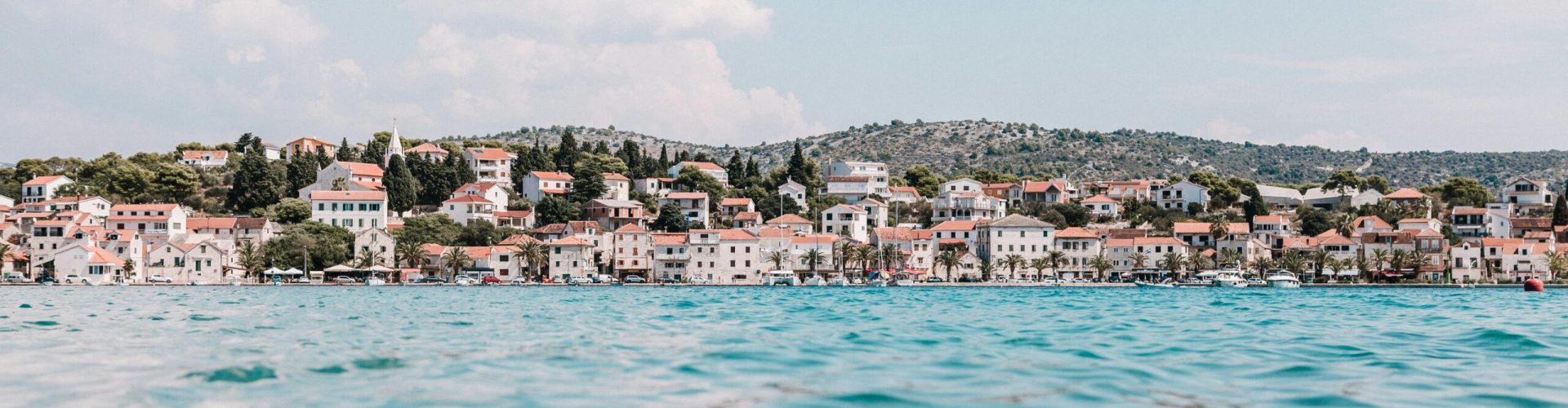 Stunning panoramic view of a coastal town in Croatia, showcasing vibrant rooftops against a calm sea.